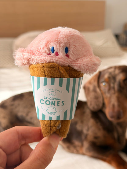 Gelato Toy pour chien, jouet cache-friandises rose en forme de glace avec teckel en arrière-plan.