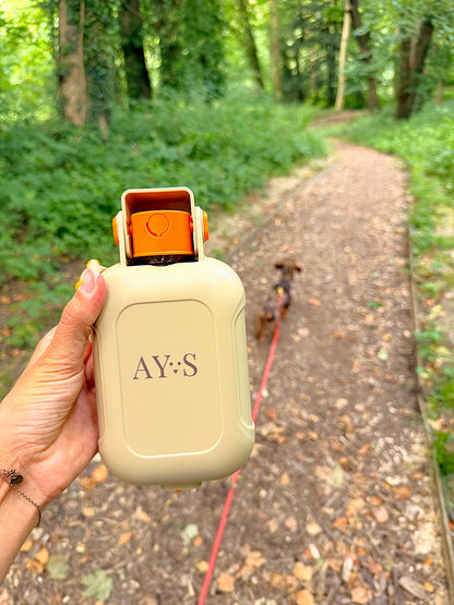 Gourde portable 2-en-1 AYOS tenue en main lors d’une promenade en forêt avec un chien.