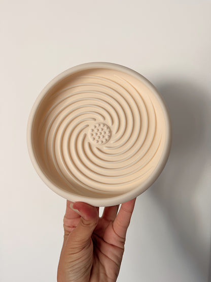 Tapis de léchage pour chien Nuage en silicone alimentaire beige présenté dans une main pour montrer ses dimensions.