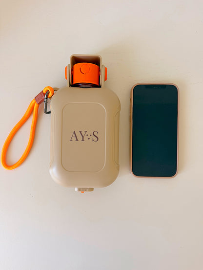 Gourde pour chien 460 ml AYOS Club avec gamelle intégrée, comparée à un téléphone pour montrer son format compact idéal pour les balades.