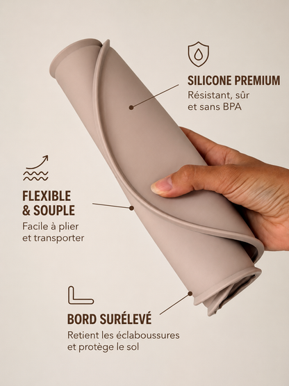 Tapis de gamelle en silicone souple AYOS Club plié à la main pour démontrer sa flexibilité, avec bord surélevé anti-éclaboussures protégeant le sol.
